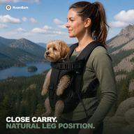 Woman at a mountain overlook with her small dog carried against her chest, front legs through the openings.